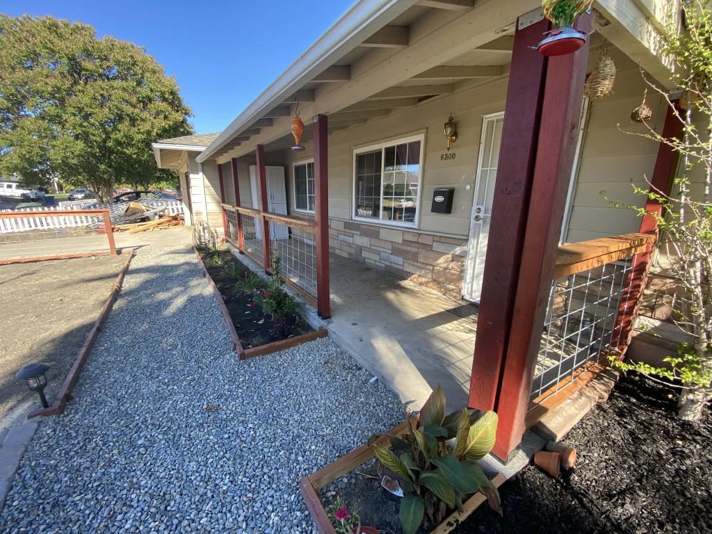 Front porch with gravel path, planter beds, and wood railing