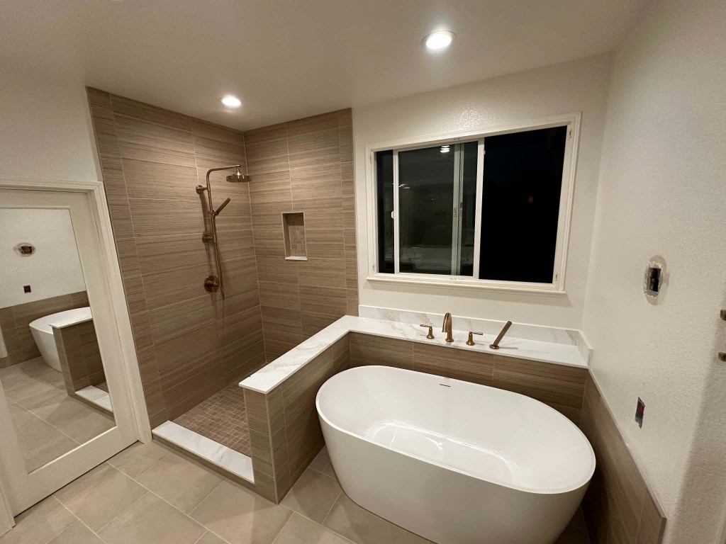 Finished bathroom with walk-in shower, freestanding tub, and brass fixtures